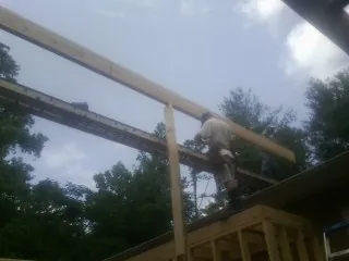 Carpenter setting a ridge beam over a new addition frame — Ice Dam Removal by Roofing Brothers in Hurley