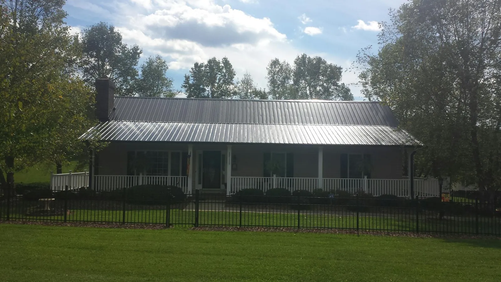 Gray metal roof on a brick ranch with a full width front porch — Gutter Guard Installation work by our crew in Hurley