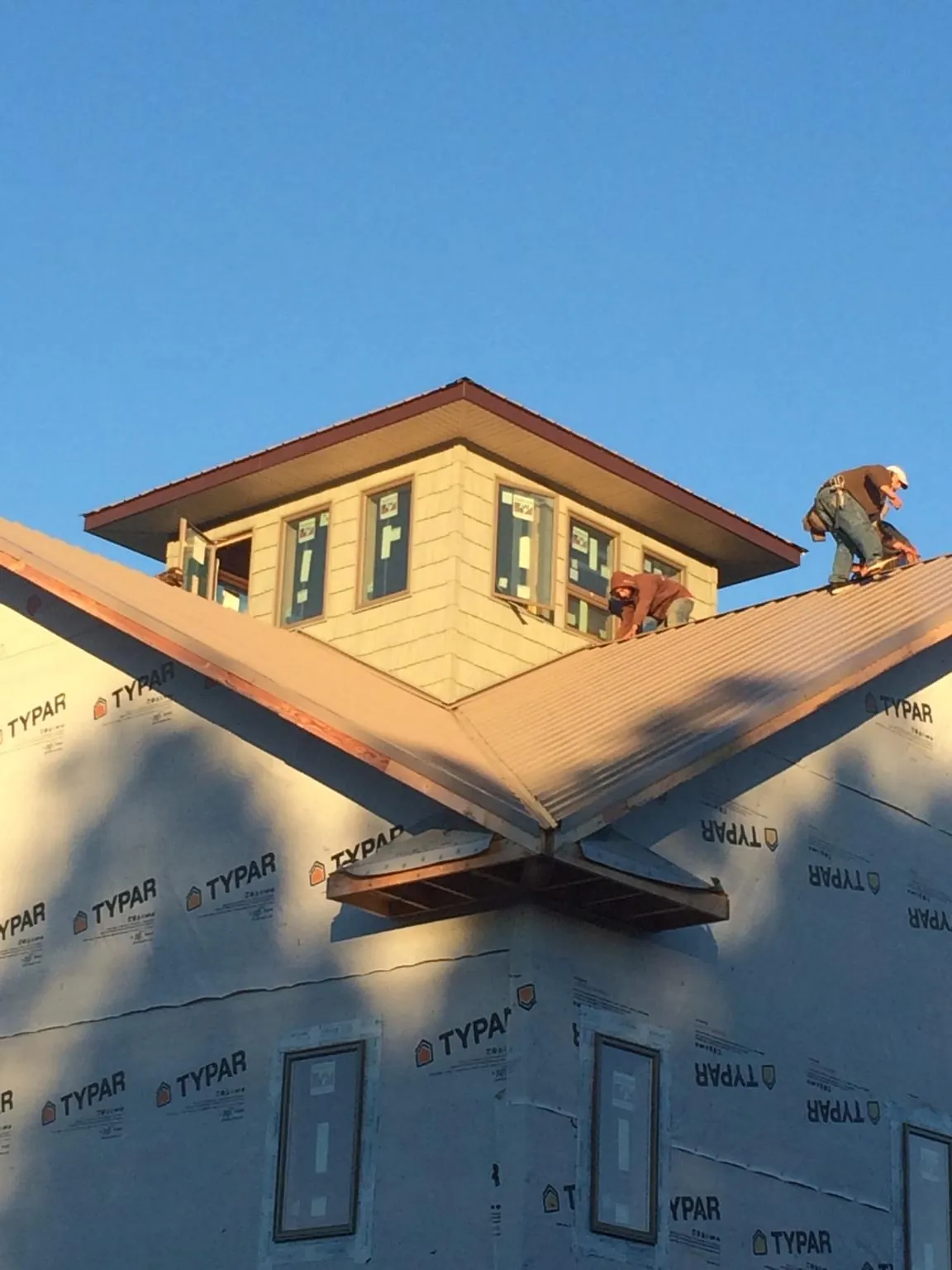 Roofers working around a rooftop cupola on a new metal roof at sunset — Roof Waterproofing in Hurley by Roofing Brothers
